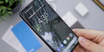 Android phone held in a hand while displaying the home screen
