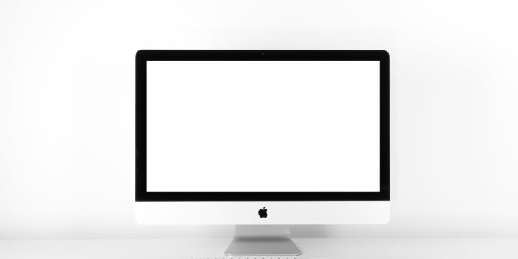 Apple Mac desktop computer, on a white desk with a white background