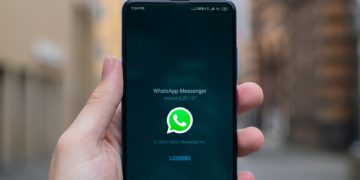 An android phone being held up in front at eye level. The whatsapp application is being opened