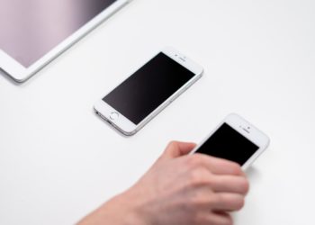 an iPad and two generations of iPhone are laid out next to each other, from largest to smallest