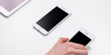 an iPad and two generations of iPhone are laid out next to each other, from largest to smallest