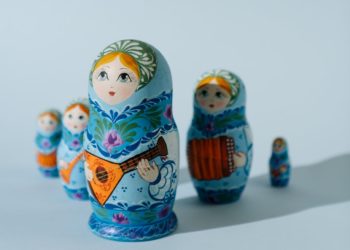 Russian dolls lined up unevenly. Shadow falls over the ones behind the largest.
