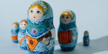 Russian dolls lined up unevenly. Shadow falls over the ones behind the largest.