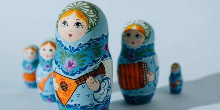 Russian dolls lined up unevenly. Shadow falls over the ones behind the largest.