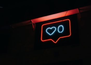 Instagram notification symbol in neon lights, with a white heart and a white 0 next to it