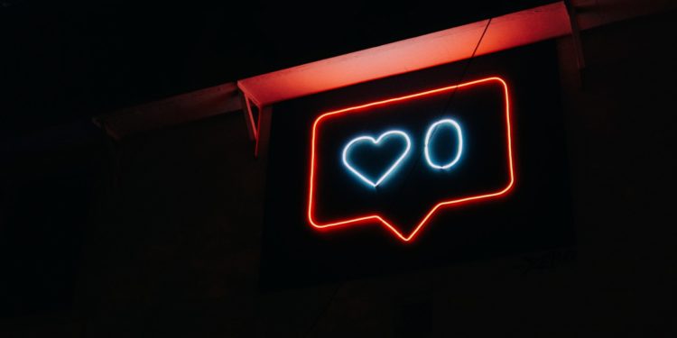 Instagram notification symbol in neon lights, with a white heart and a white 0 next to it
