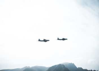 Two aeroplane silhouettes seen flying across mountains