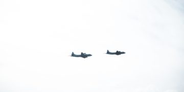 Two aeroplane silhouettes seen flying across mountains