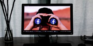 Computer desktop displaying man with binoculars that have the FB logo in the lenses