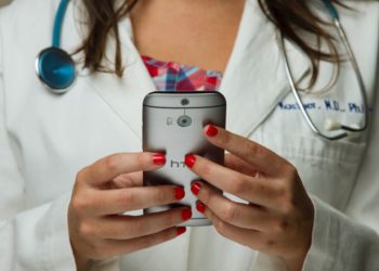 Doctor using a mobile phone wearing a stethoscope