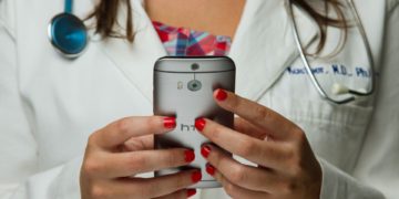 Doctor using a mobile phone wearing a stethoscope