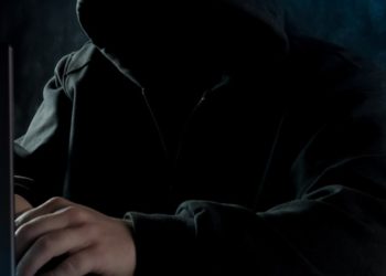 Hacker in black hoodie on computer