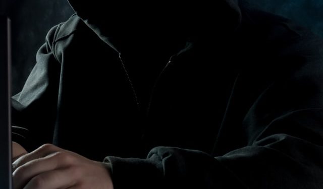 Hacker in black hoodie on computer