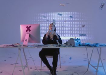 Woman sitting by computer with lots of cash around her - cybercriminal