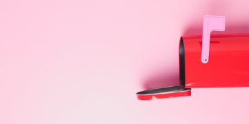 Pink mail box on a pink background with open letterbox