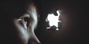 person peeping through hole
