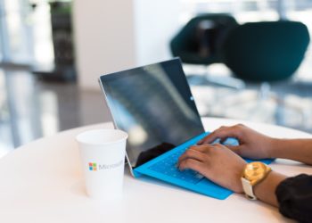 Person using blue laptop next to coffee cup