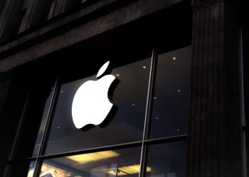 A white Apple logo above a dimly lit Apple Store.