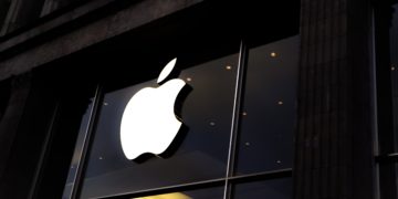 A white Apple logo above a dimly lit Apple Store.
