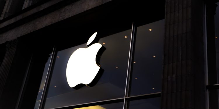 A white Apple logo above a dimly lit Apple Store.