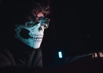 Man wearing mask, dark room.