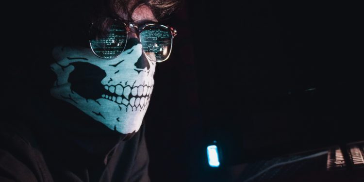 Man wearing mask, dark room.
