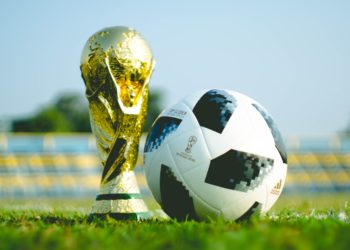 Gold trophy on Grass Next to Football