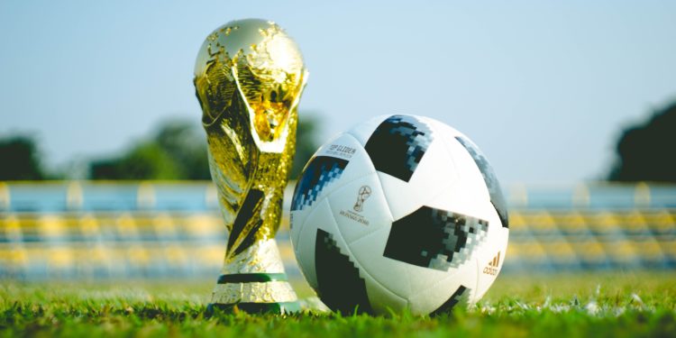 Gold trophy on Grass Next to Football