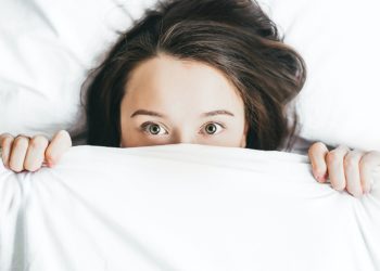 Woman hiding under bed sheet