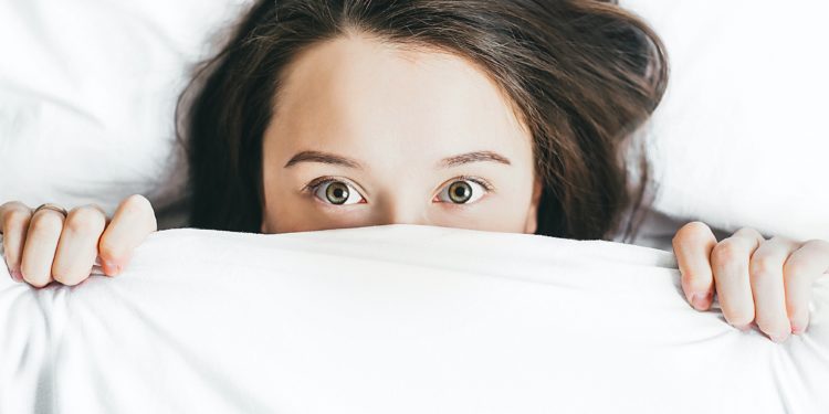 Woman hiding under bed sheet