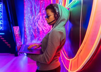 female hacker with headphones on holding laptop