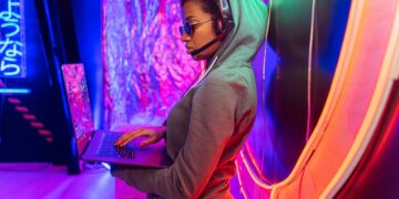 female hacker with headphones on holding laptop
